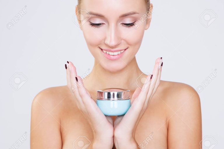 Portrait of beautiful women with perfect skin holding cream on grey background